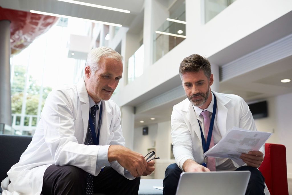 Two male doctors meeting to review new clinical information in the hospital lobby